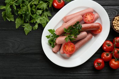 Delicious vegetarian sausages with parsley, tomatoes and soybeans on black wooden table, flat lay