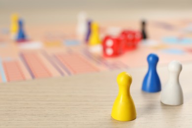 Closeup view of colorful pawns on wooden table, space for text. Board game