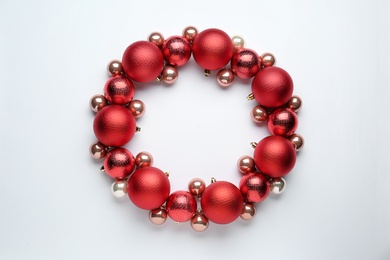 Beautiful festive wreath made of red Christmas balls on white background, top view