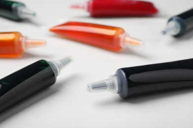 Photo of Tubes with different food coloring on white background, closeup