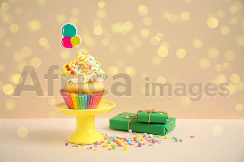 Birthday cupcake and gift boxes on beige background. Bokeh effect