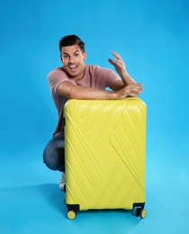 Excited man with suitcase for summer trip on blue background. Vacation travel