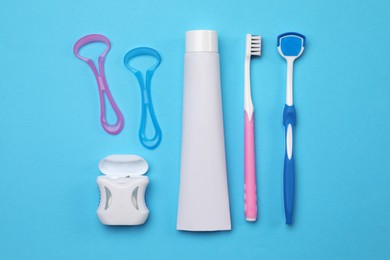 Flat lay composition with tongue cleaners and teeth care products on light blue background
