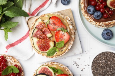 Tasty crispbreads with different toppings on white table, flat lay