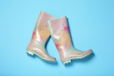 Pair of rubber boots on light blue background, top view