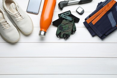 Flat lay composition with different cycling accessories on white wooden background, space for text