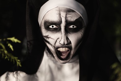 Photo of Portrait of scary devilish nun outdoors, closeup. Halloween party look