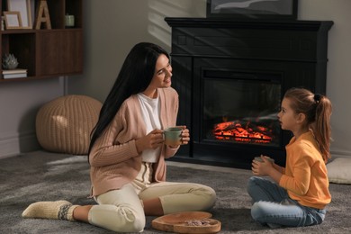 Happy mother and daughter spending time together on floor near fireplace at home