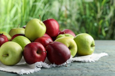Fresh ripe red and green apples on light blue wooden table outdoors