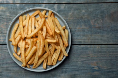 Tasty french fries on wooden table, top view. Space for text