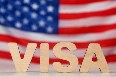 Photo of Word Visa made of wooden letters on light grey table against American flag