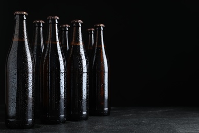 Photo of Bottles of beer on table against black background. Space for text
