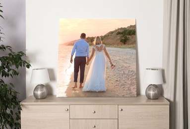 Canvas with printed photo of bride and groom walking at sunset on chest of drawers in room