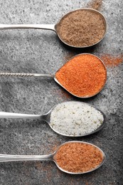 Different kinds of salt on grey table, flat lay