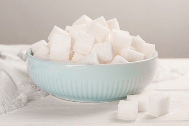 Photo of Bowl with sugar cubes on white table, closeup