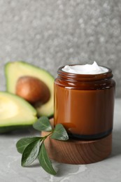 Photo of Jar of face cream and avocado on marble table