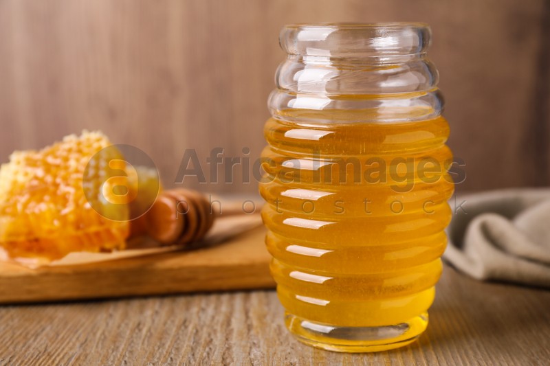 Photo of Jar of tasty aromatic honey on wooden table