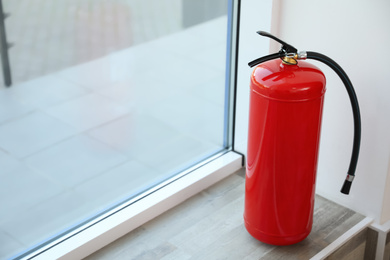 Fire extinguisher near window indoors. Space for text