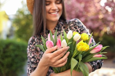 Beautiful young woman with bouquet of tulips in park, focus on hands