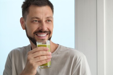 Man drinking delicious juice indoors, space for text