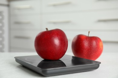 Red apples and modern digital scale on table