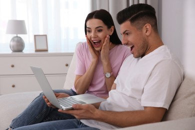 Emotional couple participating in online auction using laptop at home