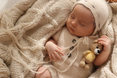 Adorable newborn baby with toy bear sleeping in basket, top view