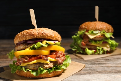 Tasty burgers with bacon on table. Space for text