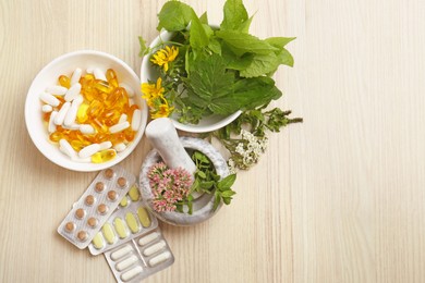 Mortar with fresh herbs and pills on wooden table, flat lay. Space for text