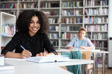 Photo of Young African-American woman studying at table in library