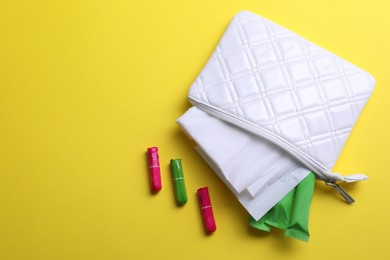 Bag with menstrual pads and tampons on yellow background, flat lay. Space for text