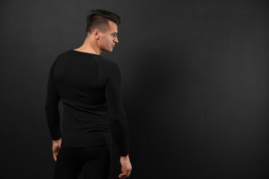 Man wearing thermal underwear on black background. Space for text