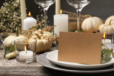 Beautiful autumn place setting with blank card and decor on wooden table, space for text
