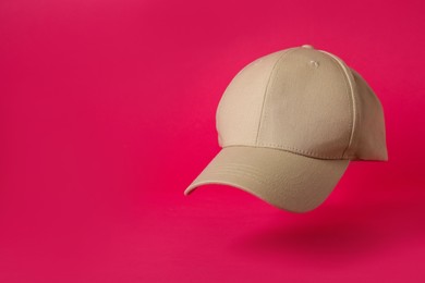 Baseball cap on pink background, space for text