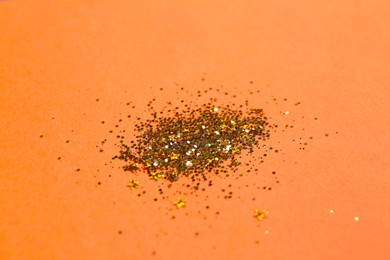 Shiny bright golden glitter on pale coral background, closeup