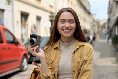 Photo of Young woman with camera on city street. Interesting hobby