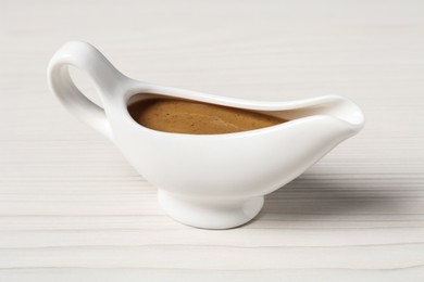 Delicious turkey gravy in sauce boat on white wooden table