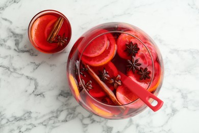Glass and bowl of delicious aromatic punch drink on white marble table, flat lay