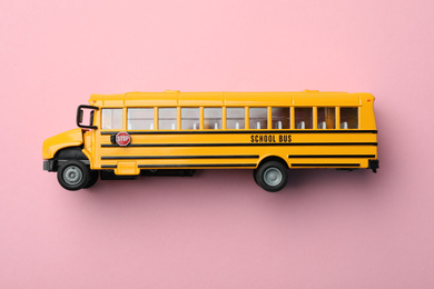 Yellow school bus on pink background, top view. Transport for students