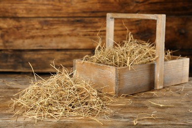 Heap of dried hay and crate on wooden table