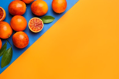 Photo of Many ripe sicilian oranges and leaves on color background, flat lay. Space for text