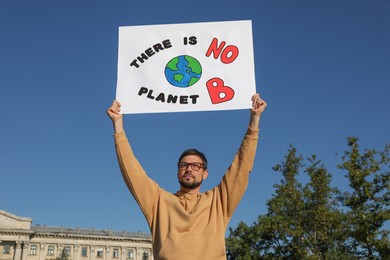 Man with poster protesting against climate change outdoors