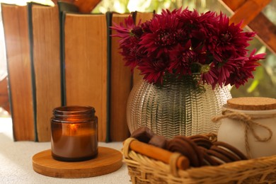 Photo of Beautiful pink chrysanthemum flowers, burning candle and sweet chocolate treats on light grey table
