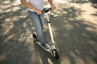 Woman riding electric kick scooter outdoors. Space for text