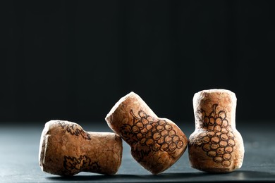 Corks of wine bottles with grape images on black table, closeup