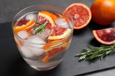 Delicious refreshing drink with sicilian orange and rosemary near fresh ingredients on grey table, closeup