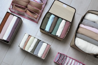 Photo of Different organizers with folded clothes and underwear on white wooden background, flat lay. Vertical storage