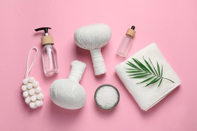 Beautiful spa composition with herbal massage bags and different care products on pink background, flat lay