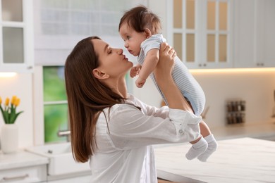Photo of Happy mother with her little baby in kitchen at home