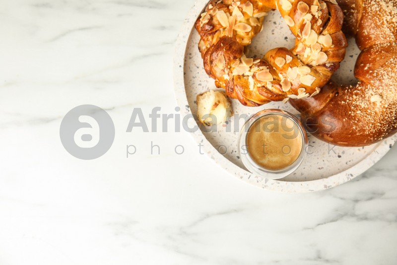Fresh tasty pastries and coffee on white marble table, top view. Space for text